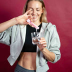 Frau ruehrt einen Aenders Daily Stick in ein Glas Wasser