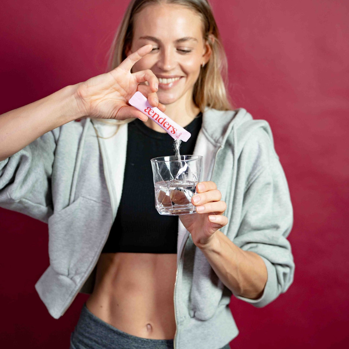 Frau ruehrt einen Aenders Daily Stick in ein Glas Wasser